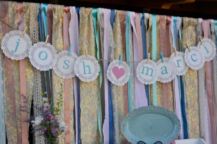 Sample picture of couple's names on dollies against hanging ribbon backdrop. 